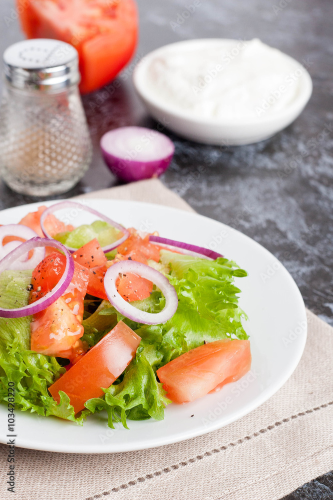 Salad with greens, tomatoes, red onions and cucumber on white pl Salad with greens, tomatoes, red onions and cucumber on white pl
