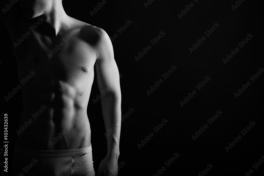 Fit young man with beautiful torso, isolated on black background