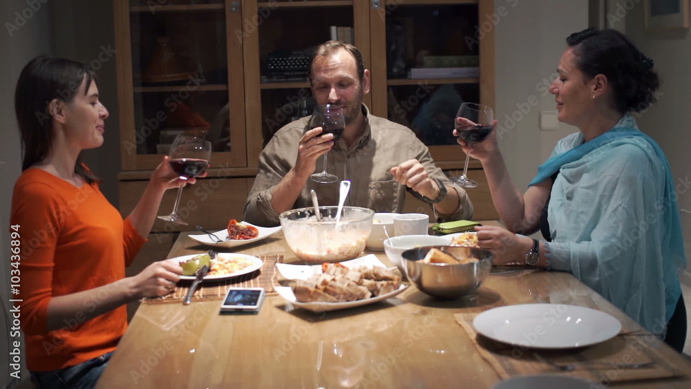 Group of friends drinking red wine by table at home
Group of friends drinking red wine by table at home