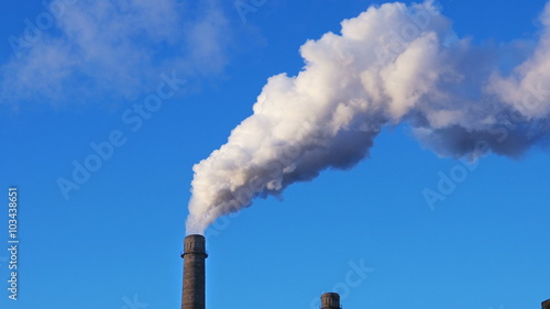 Factory plant smoke stack over blue sky background. Energy generation and air environment pollution industrial scene. 4K UHD video footage.