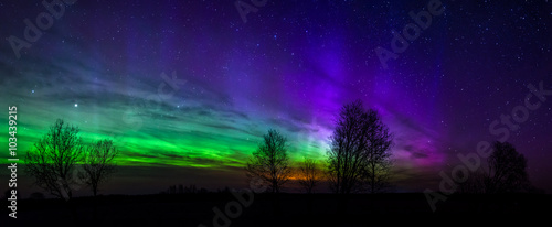Panoramic photo of green and purple Aurora Borealis in Estonia