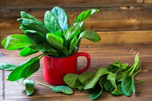 Spinach leaves in red  cup on wooden backgound
