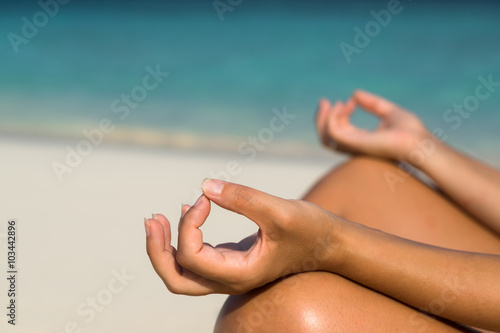 Woman sitting on the beach in lotus pose