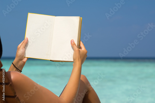 Reading book in the beach, hands holding book with blank pages,