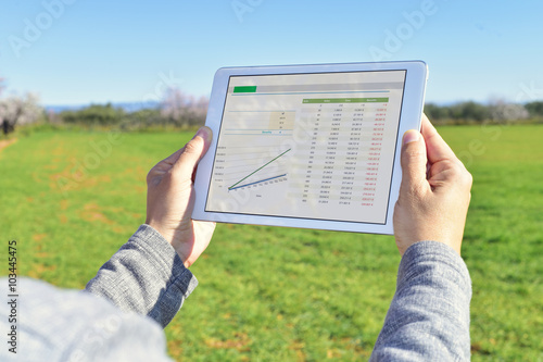 man observing some charts in a tablet in a fallow field