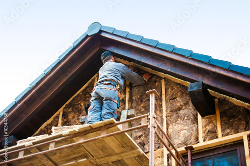 Construction worker thermally insulating house facade with glass