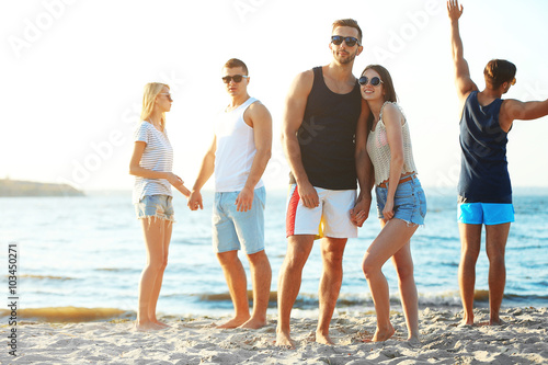 Happy couple and friends having fun at the beach, outdoors