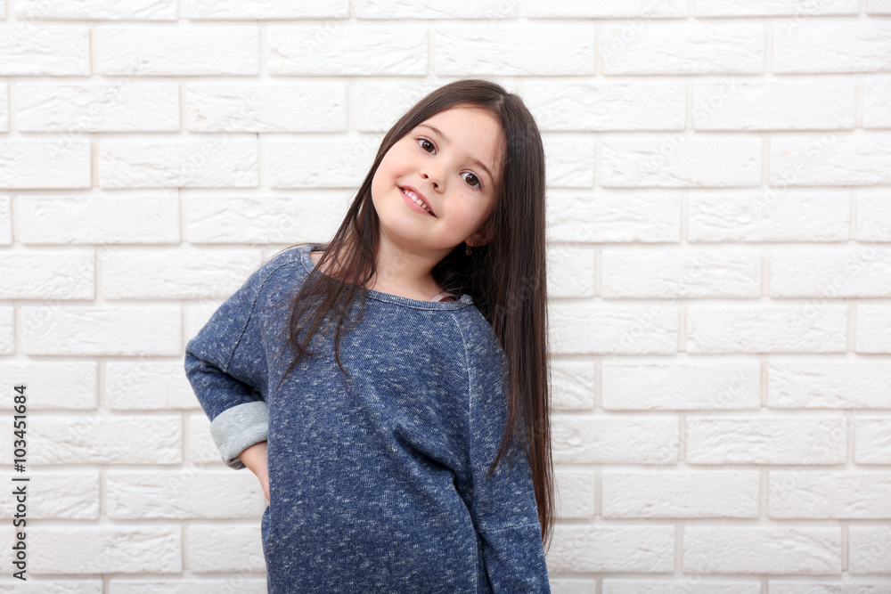 Little girl on a white brick wall background