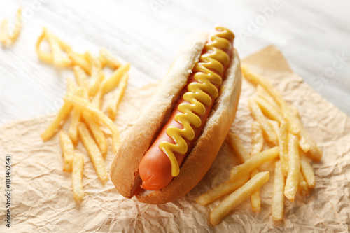 Hot dog and fried potatoes on wooden background