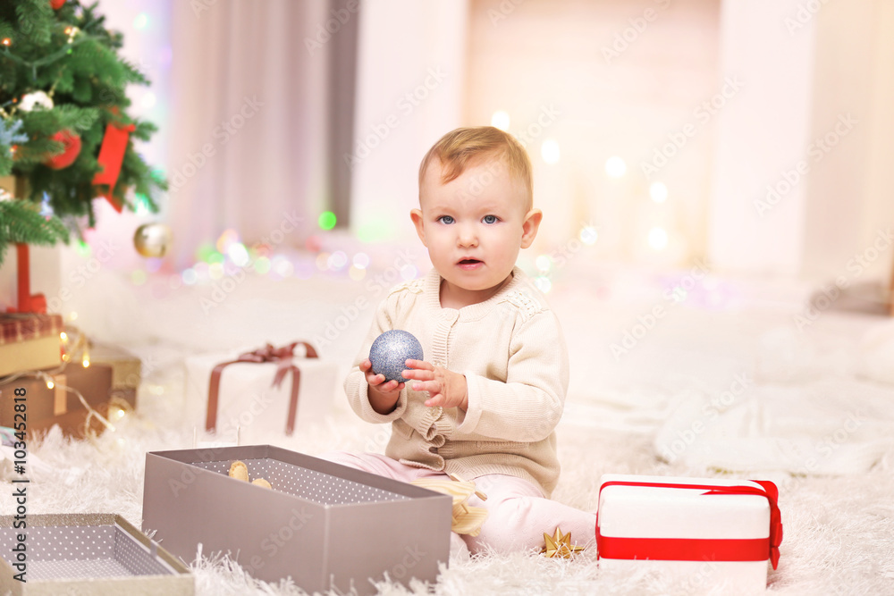 Funny baby girl with gift box in Christmas living room Funny baby girl with gift box in Christmas living room