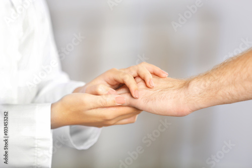 Hand of medical doctor carefully holding patient's hands