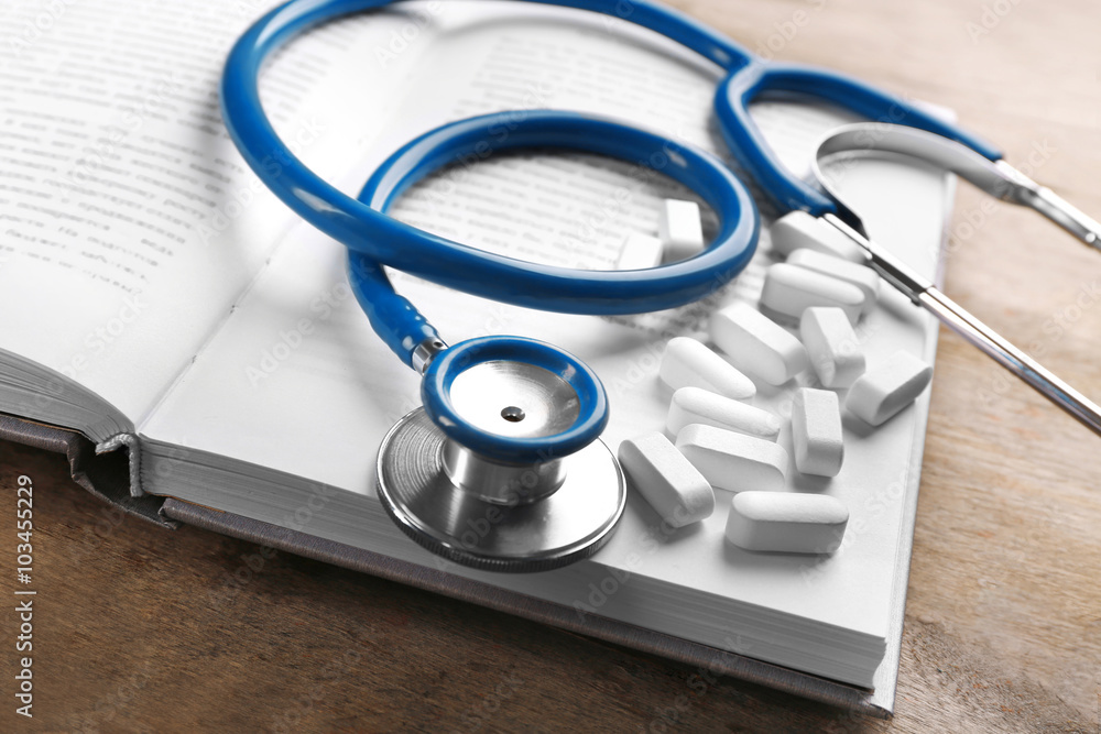 Stethoscope with pills and book, closeup Stethoscope with pills and book, closeup