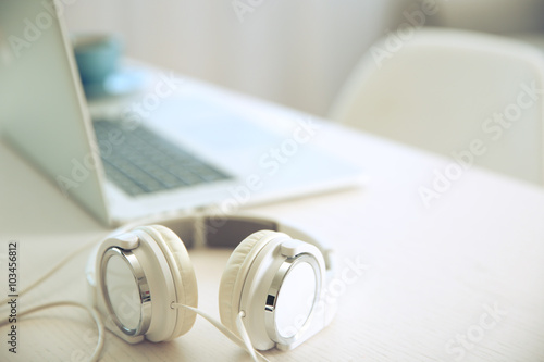 Headphones and laptop on white table against defocused background