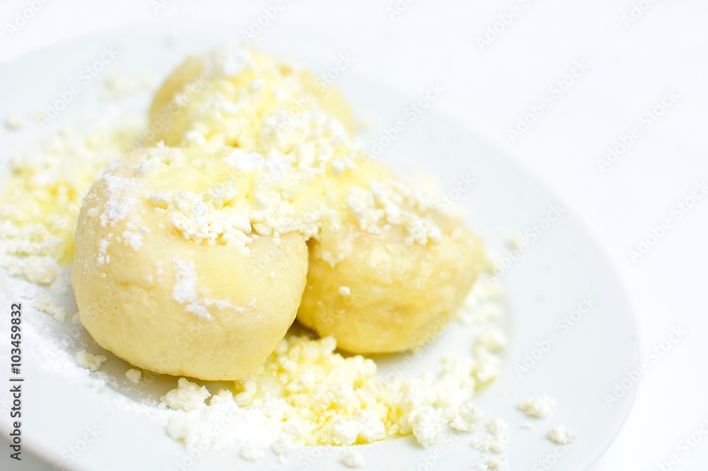 Fruit dumplings with fruit sprinkled with cheese, sugar and melted butter on white plate.