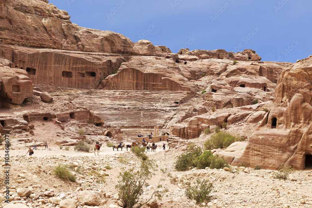 Tourists near the roman-era amphitheater carved into the pink sandstone at Petra, Jordan.