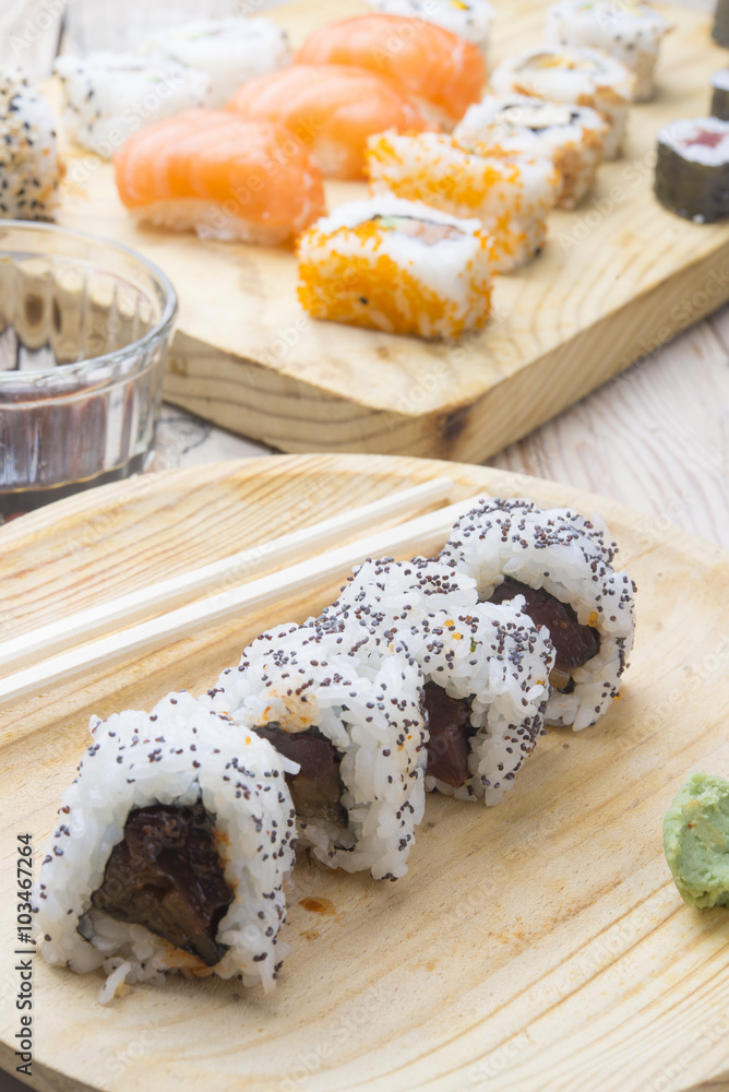 Different Sushi rolls,wasabi and ginger on a plate on wooden bac Different Sushi rolls,wasabi and ginger on a plate on wooden bac