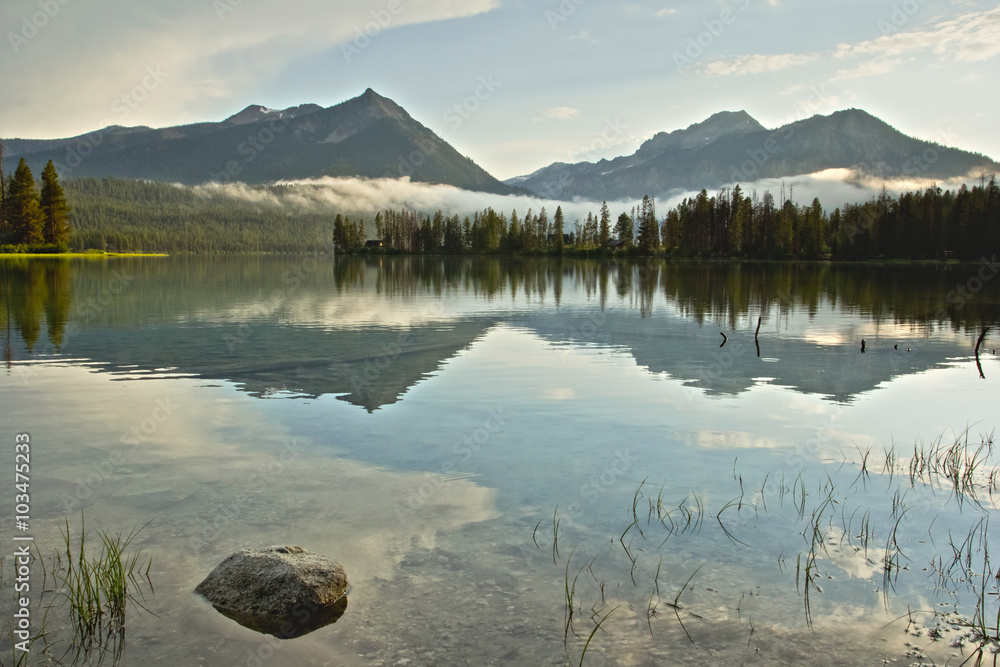 Sawtooth mountain peaks of Idaho reflected in the calm water of a lake