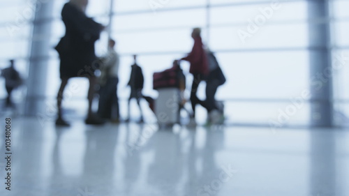 Silhouette people walking with luggage at airport terminal hall going on air plane travel. Many people walk with baggage. Out of focus blurry defocused.