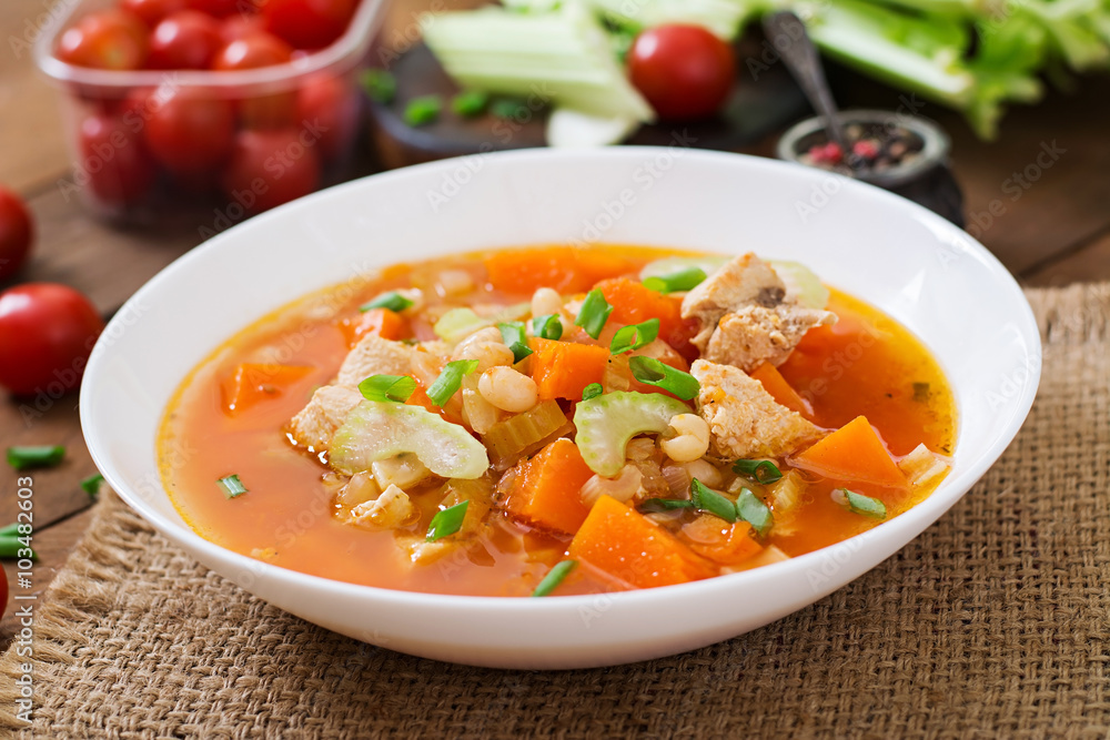 Tomato chicken soup with pumpkin, beans and celery in white bowl Tomato chicken soup with pumpkin, beans and celery in white bowl