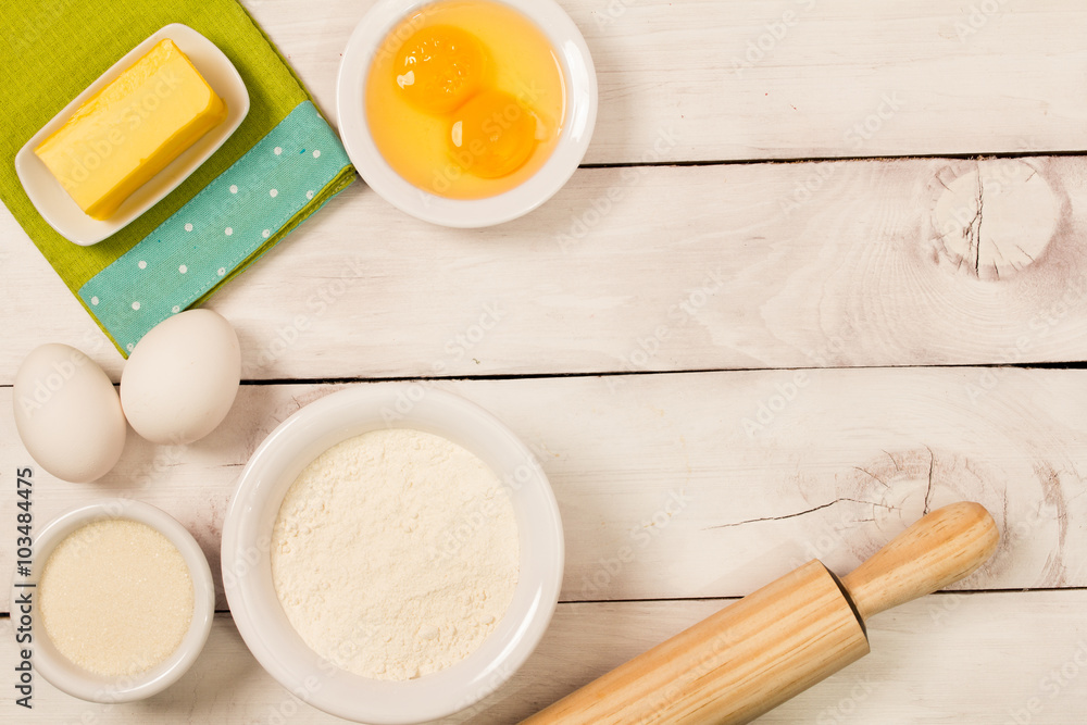 Baking in rustic kitchen recipe ingredients (eggs, flour, milk, butter, sugar) on white wooden table from above. Baking in rustic kitchen recipe ingredients (eggs, flour, milk, butter, sugar) on white wooden table from above.
