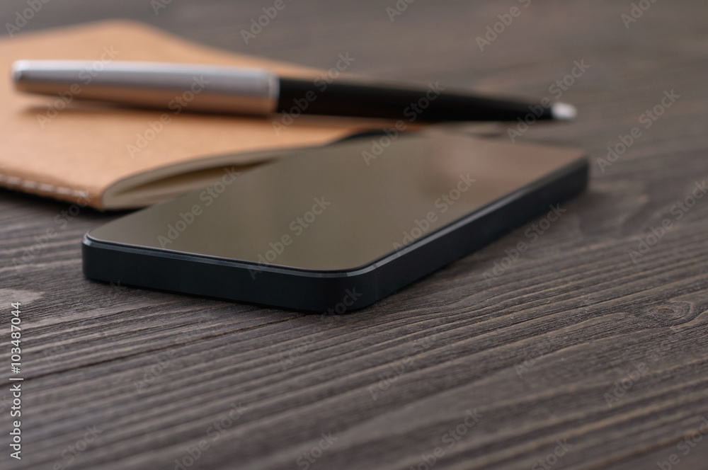 black smartphone on office workplace with notebook black smartphone on office workplace with notebook