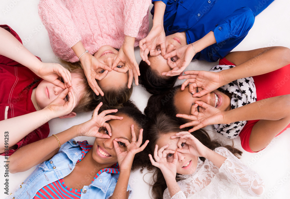 Obraz premium children lying on the floor head to head with glasses out of fingers