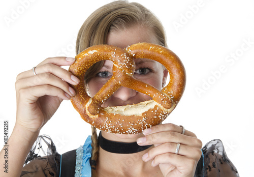 Bavarian girl in traditional clothes. She is eating a pretzel.