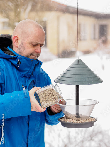 Man fills a bird feeder