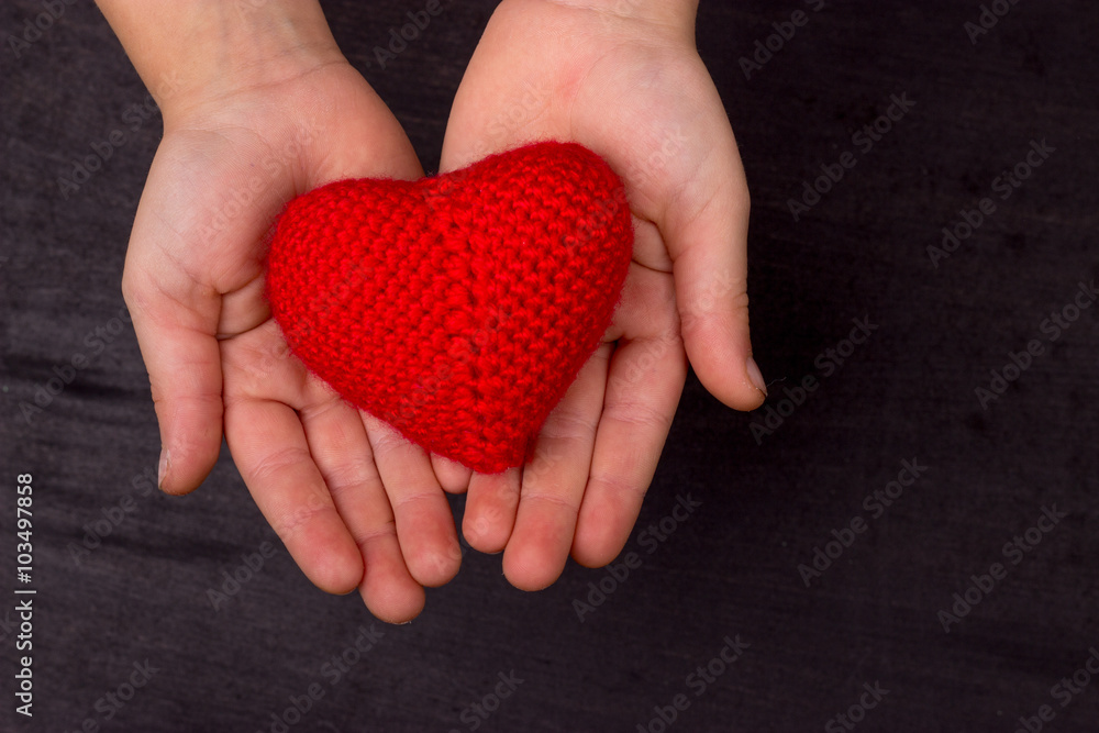 Fototapeta premium heart of red knitted crochet thread, in the children's hands