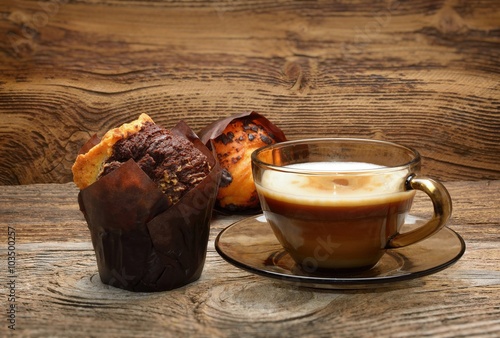 Chocolate muffins and cup of coffee on wooden background
