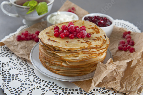 Stack of pancakes served with fresh cranberries, sour cream and