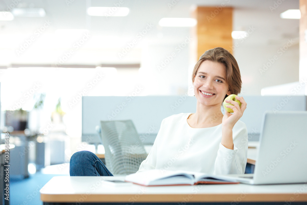 Businesswoman sitting at the desk with apple in office Businesswoman sitting at the desk with apple in office