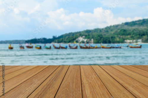 Wood table top on blurred beach background with long tail boat for presentation product.