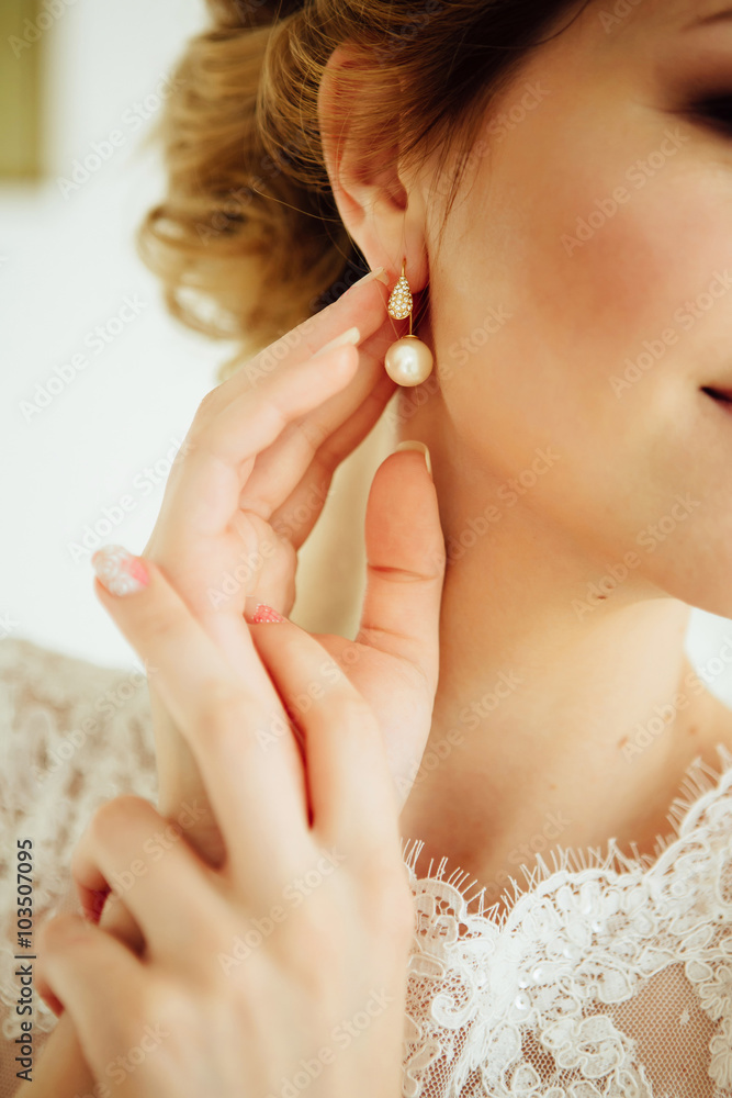 Beautiful bride in the morning puts on earring. Beautiful bride in the morning puts on earring.