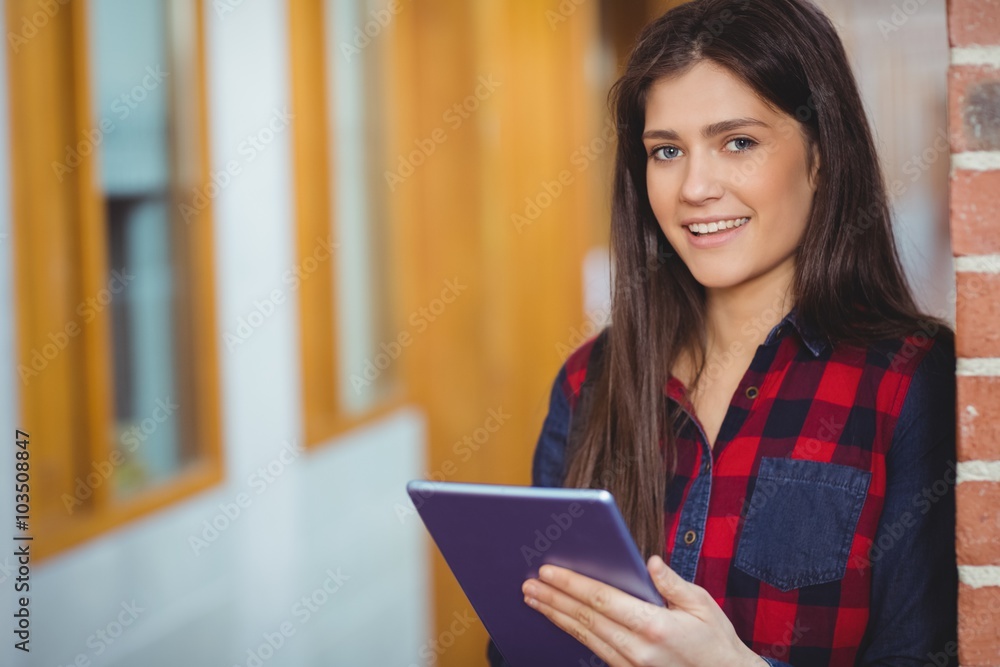 Smiling student using tablet in the hallway Smiling student using tablet in the hallway