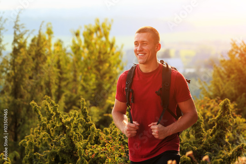 Close up of smiling young man hiking with backpack