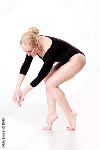 blonde ballet dancer in black swimsuit dancing in white studio