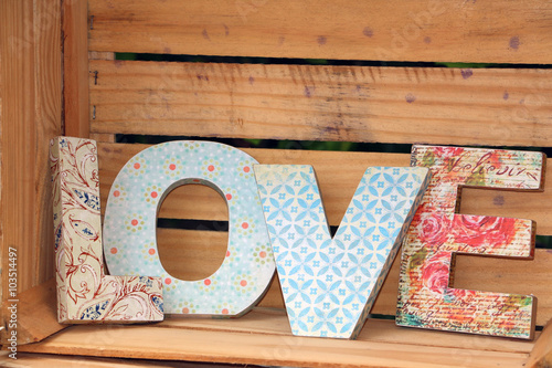 LOVE written with colorful wooden letters decorated in decoupage technique posted on wooden pallet