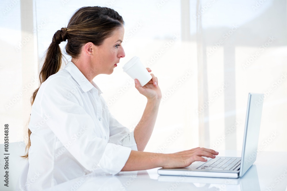 woman on her laptop drinking a coffee woman on her laptop drinking a coffee