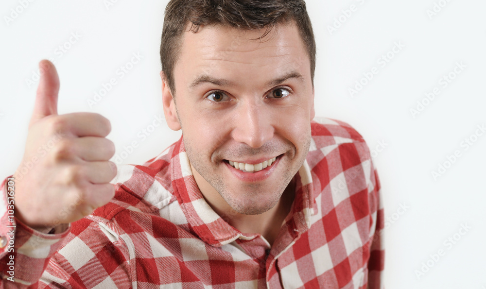 Smiling young man in hipster shirt showing thumb up and standing against white background Smiling young man in hipster shirt showing thumb up and standing against white background