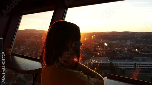 Pensive woman is looking at sunsetcity photo