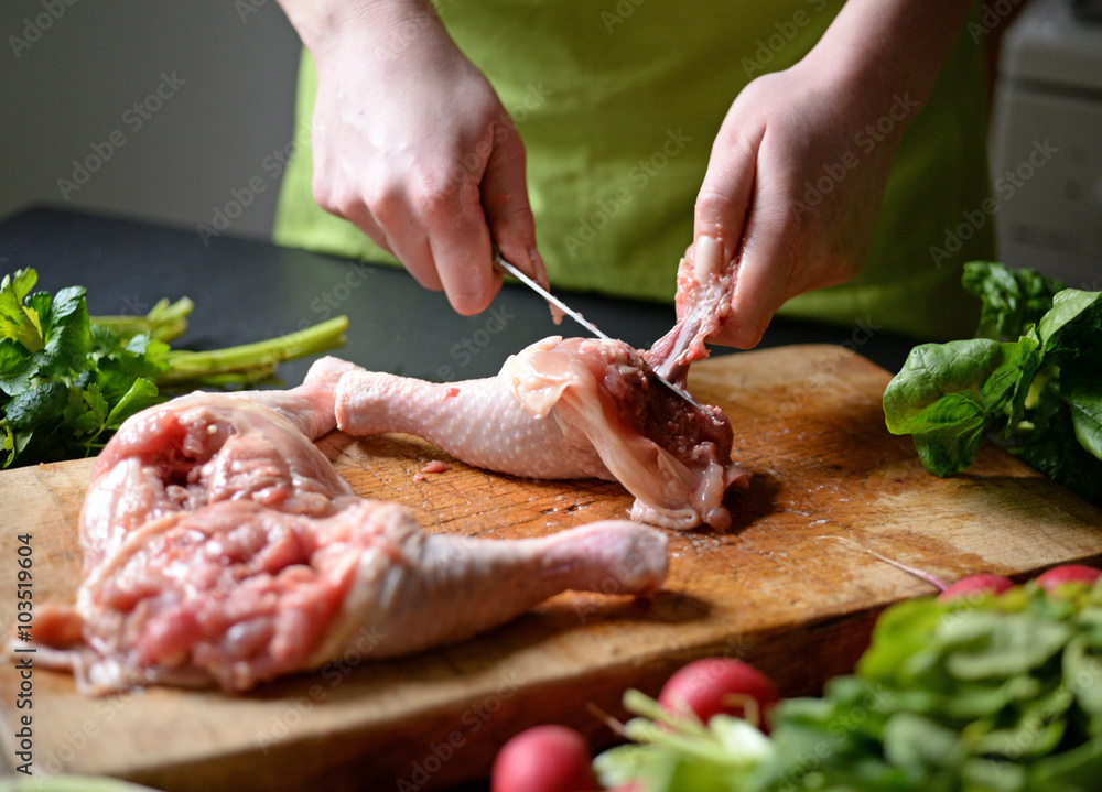 Young woman preparing chicken with vegetables