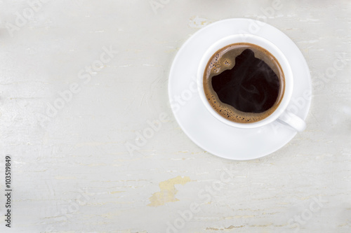 A cup of coffee on a wooden table.A cup of coffee on an old painted,wooden,white background.