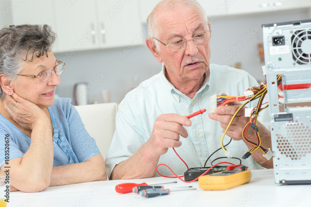Retired man testing computer with multimeter Retired man testing computer with multimeter