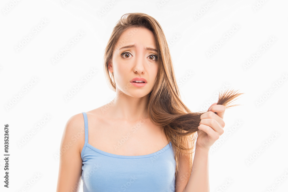Sad unhappy young girl showing her damaged split ends Sad unhappy young girl showing her damaged split ends