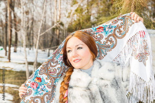 Portrait of young caucasian woman in traditional russian pavloposadskie  folk scarf on head. Russian style on a background of snow. photo