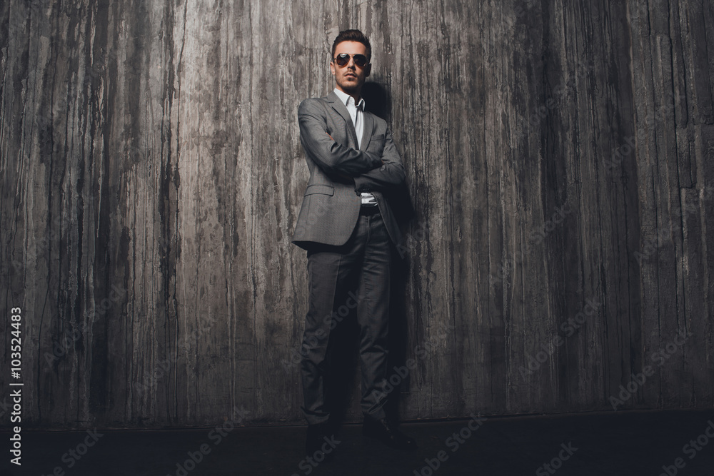 Handome rigid man with glasses in suit on the grey background cr Handome rigid man with glasses in suit on the grey background cr