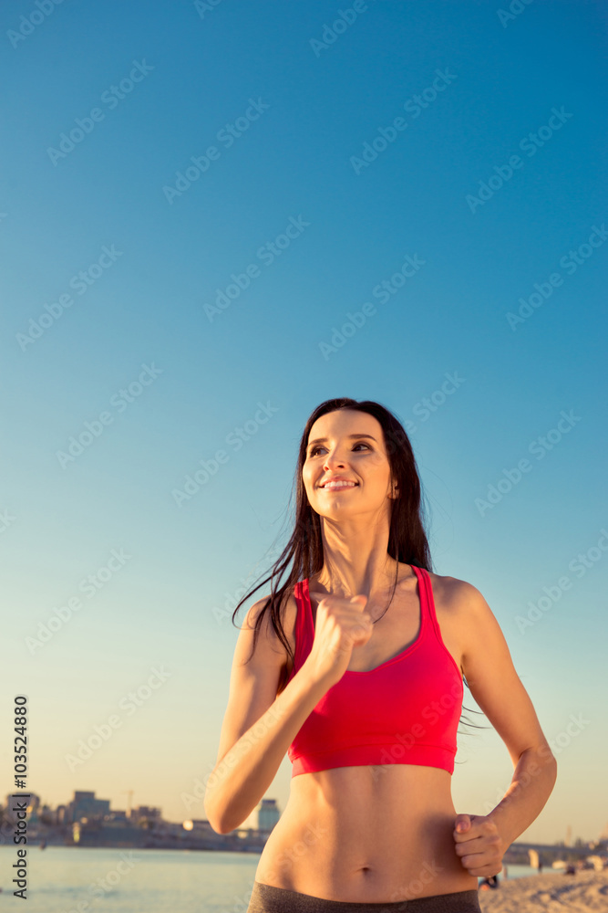 Healthy young girl running on the beach on the background of sky