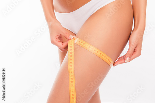 Close up photoof sexy woman measuring her leg's size with tape m