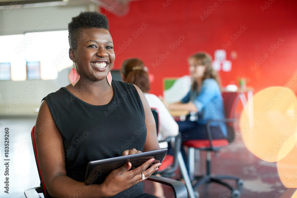 Confident female designer working on a digital tablet in red creative office space Confident female designer working on a digital tablet in red creative office space
